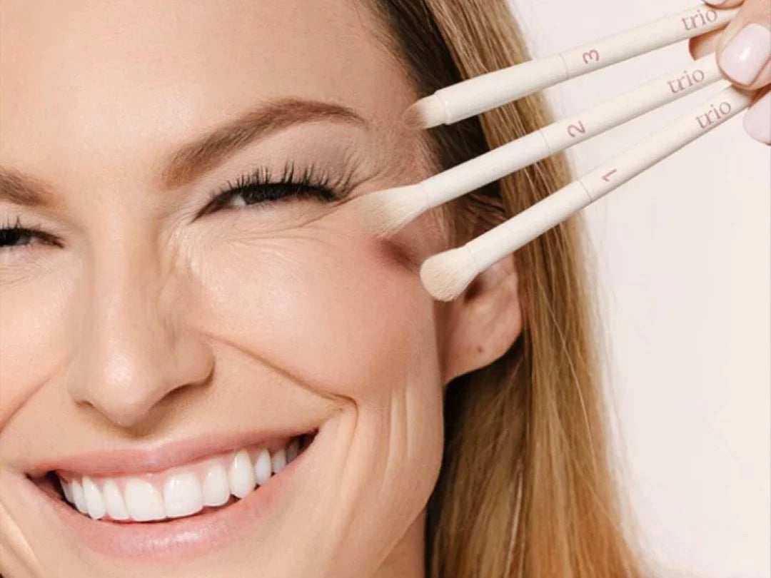 smiling woman holding 3 eyeshadow brushes
